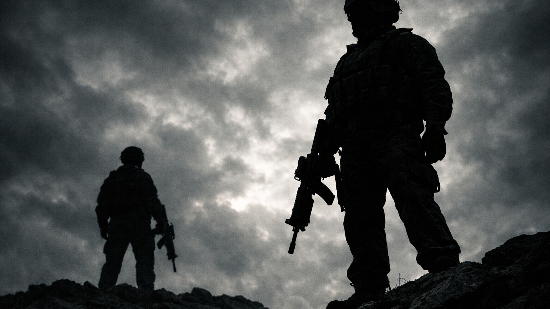 Two soldiers in full gear, seen only as dark silhouettes. Standing on a rocky ridge slightly elevated. On closer (right), one further (left), each holding a rifle at their side, low angle shot (camera looking up), dramatic cloudy sky, overcast. Strong backlighting, subjects completely blacked out, muted desaturated tones (almost monochrome) mood : Tense, cinematic, gritty