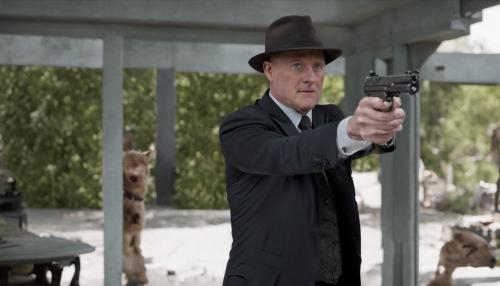 raymon reddington con su arma disparandola